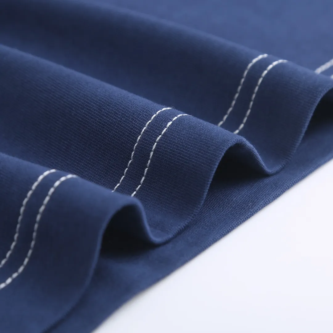 AMI Love A Embroidered Short Sleeve Fabric Selection: High-count pure cotton is selected, with moderate weight and natural drape. The cotton fiber itself has good moisture absorption and breathability, which can quickly absorb sweat and dissipate it outwards. At the same time, it feels soft and delicate, and it is non-itchy when worn next to the skin. After the pre-shrinking process, the washing shrinkage is greatly reduced, and it is not easy to deform after repeated machine washing. Craftsmanship: 1: The advanced computing system of imported embroidery machines is used to depict the contour lines of the love A pattern. White embroidery thread and Tibetan Blue fabric form a soft contrast, with neat edges, no skipping lines, and no burrs. The pattern is full and three-dimensional, and the texture is delicate. 2. Make dark embroidery of letters of the same color on the back neckline, using embroidery threads of the same color as the fabric, which is low-key and not obtrusive, and does not destroy the overall simple style. The back of the embroidered product is flat and has no bulges, and will not irritate the skin, taking into account both beauty and wearing comfort. Sewing details: 1: The collar, cuffs, hem, and shoulder lines are all made of contrasting topstitching and double-turn craftsmanship. The neatly routed threads form a sharp contrast with the Tibetan Blue fabric and outline the outline of the clothes. 2: The internal seams of the clothes are all treated with overlocking technology, without excess burrs or threads, and the details are clean and tidy; the hem and cuffs are made with double-folding stitching technology, and the edges are smooth and not frizzy to avoid curling and curling when wearing. Accessories: One-to-one customized three-standard Size: S M L XL Style No. D 292